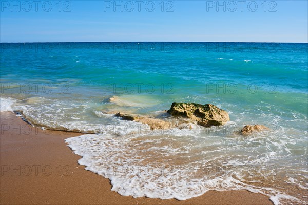 Breaking waves on a sandy beach with a rock