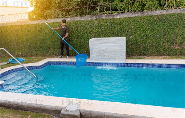 Maintenance person cleaning a swimming pool with skimmer