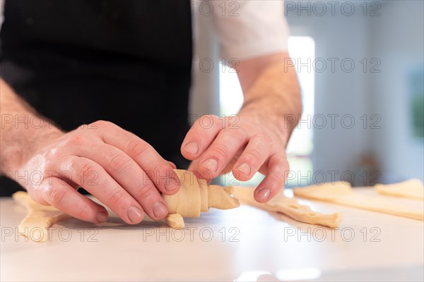 Hands of a man baking croissants
