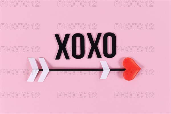 Valentine's day love arrow and XOXO text on pink background