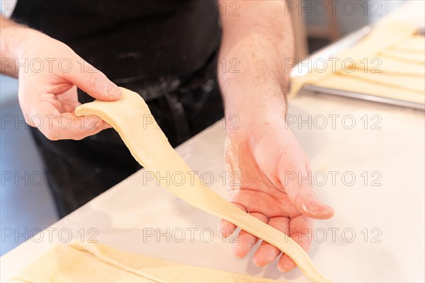 Detail of the hands of a man baking croissants collecting the triangular cuts of the puff pastry
