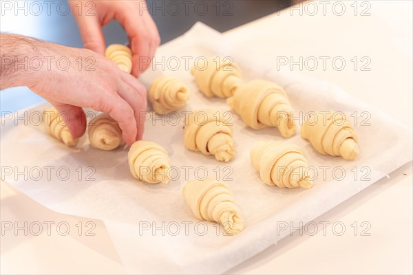 Hands of a man baking small croissants at home