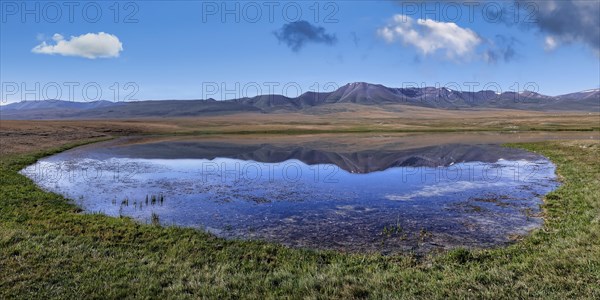 Mountains reflecting in a lake along the At-Bashy Range