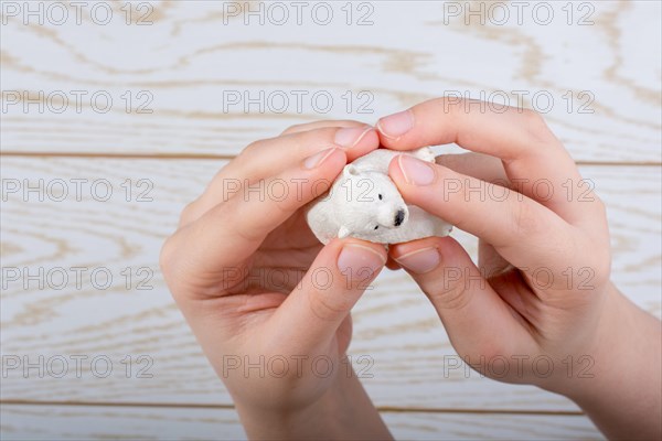 Hand holding a Polar bear model on a wooden background