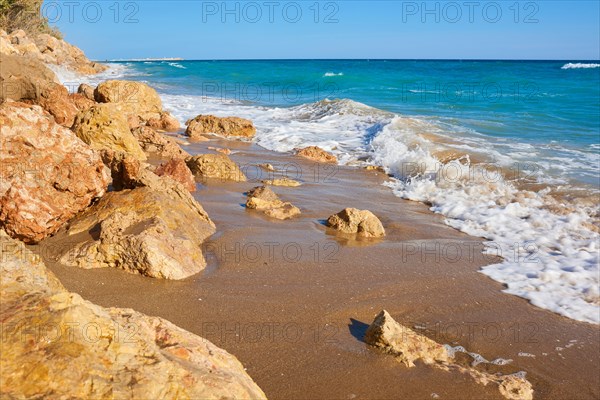 Breaking waves on a sandy beach with a view rocks