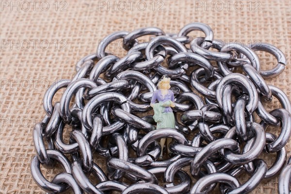 Woman figurine on steel chains on a textured surface on display