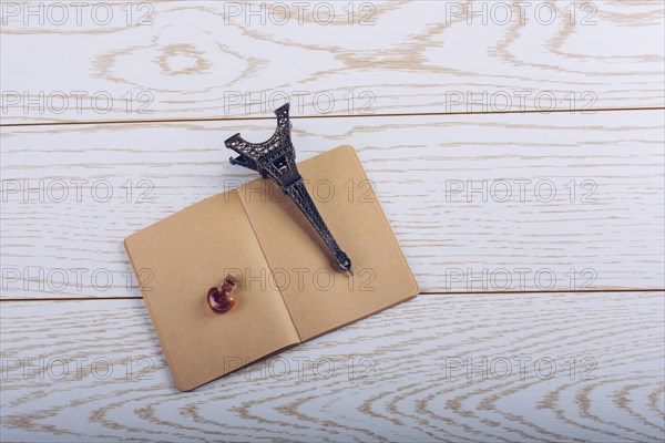 Eiffel tower miniature and a potion bottle on a brown notebook on a wooden background