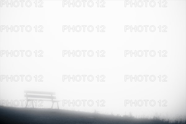 Mountain meadow with bench and fog in the background