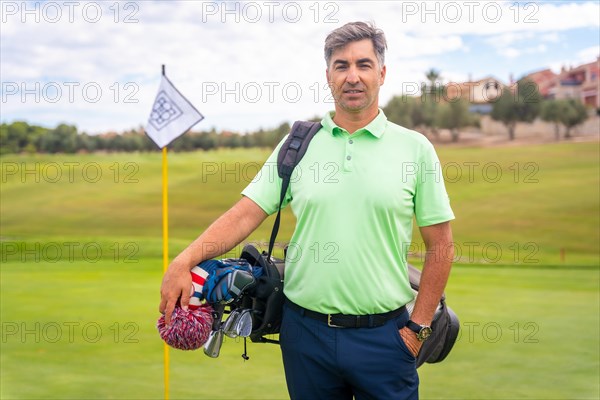 Portrait of a man playing golf together with the clubs on the green