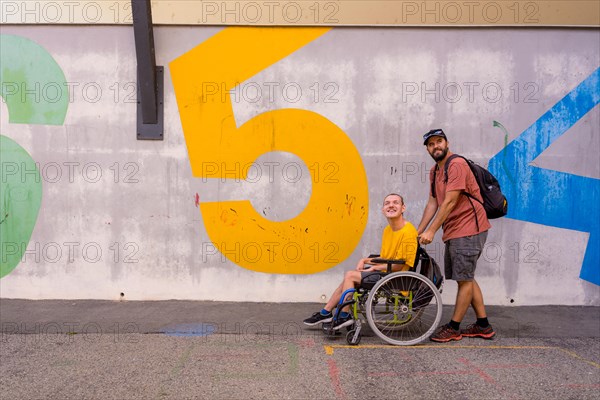 A disabled person in a wheelchair with a cement wall