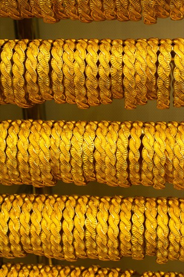 Shop display of dozens of golden bracelets and bangles