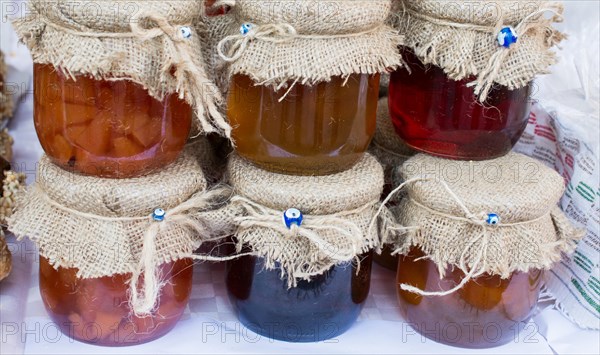 Various colored honey jars with fabric on lid in display