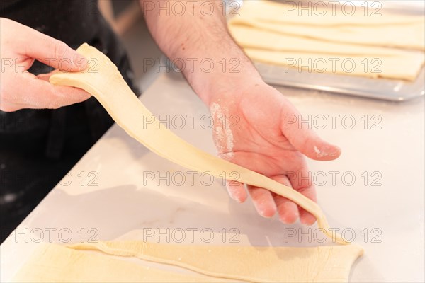 Detail of the hands of a man baking croissants making triangular cuts in the puff pastry