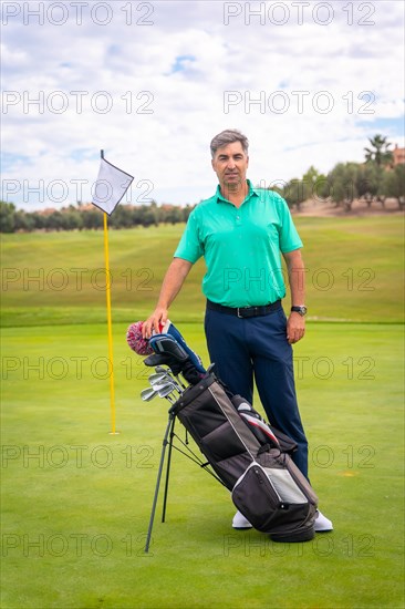 Portrait of a man playing golf along with the clubs on the green