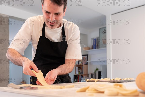 A man baking croissants picking up the triangular cuts from the puff pastry