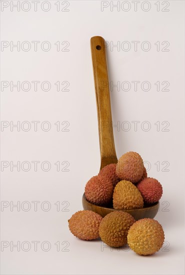 Fresh lychees in a wooden spoon isolated on a white background