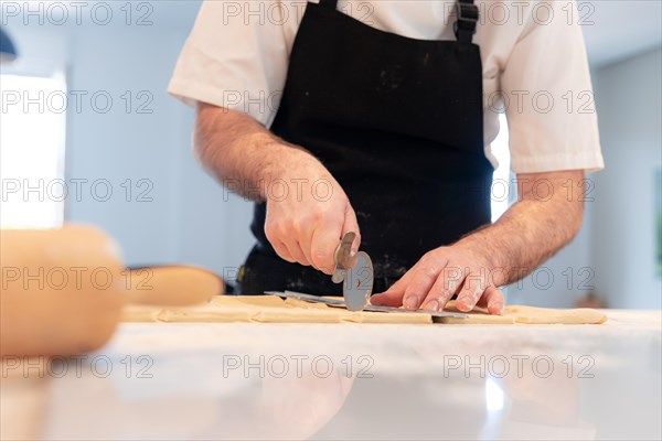 Detail of the hands of a man baking croissants