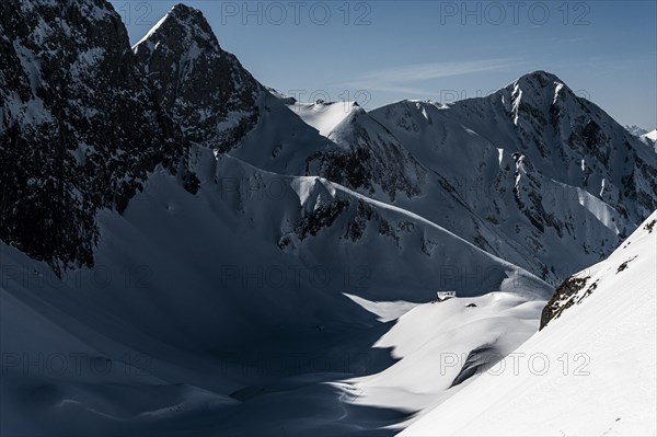 Mountain hut in deep snowy mountain landscape with light and shadow