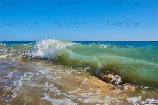 Breaking waves on a sandy beach with a rock