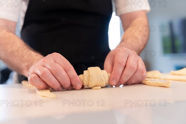 Hands of a man baking small croissants at home