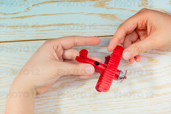 Hand holding a red toy plane on a on wooden texture