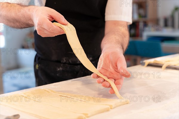 Detail of the hands of a man baking croissants collecting the triangular cuts of the puff pastry