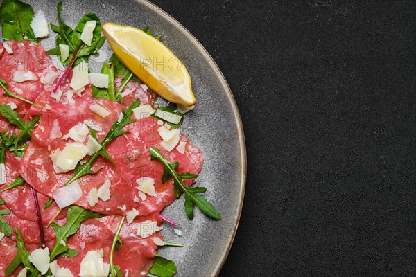 Top view of marbled beef carpaccio with arugula and chard leaves