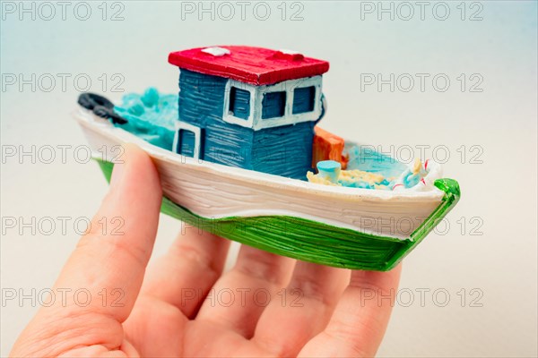 Little colorful model fishing boat in hand on white