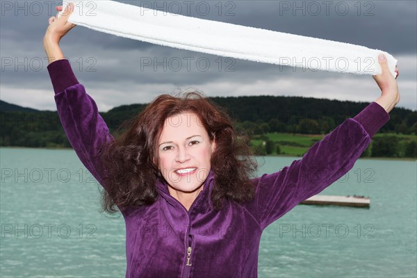 Woman standing by the lake holding white towel