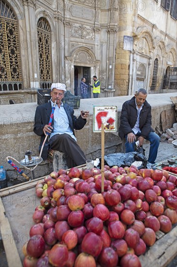 Egyptian man smoking shisha or hookah at a fruit stall