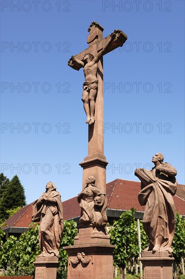 Christ cross with sculptures of saints against blue sky