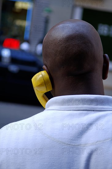 Coloured New Yorker talking on the phone with a yellow handset