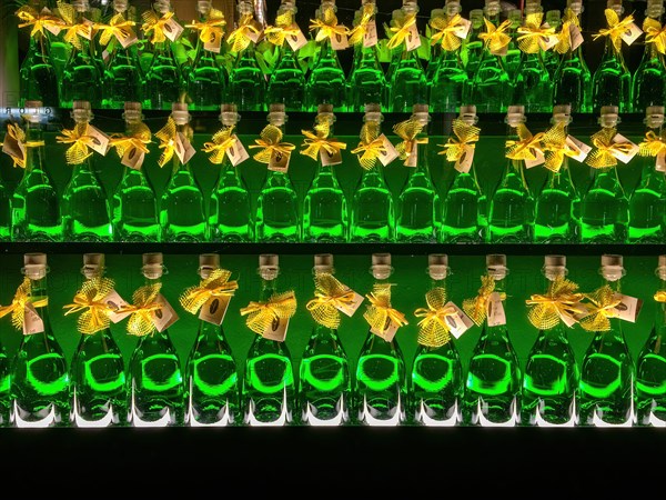 Three rows of bottles with alcoholic high-proof drink green absinthe