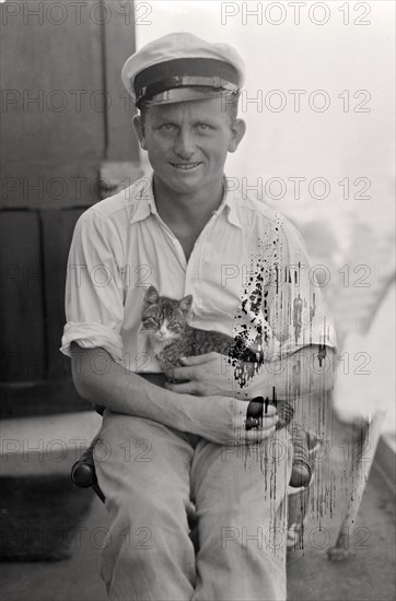 Sailor with cat in his arms on board a cargo ship