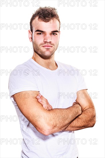 Unshaven confident handsome macho man looking at camera with folded arms and serious expression in casual t-shirt