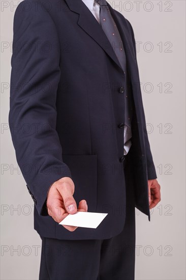 Torso view of a male businessman handing over a blank white business card with his credentials and company name