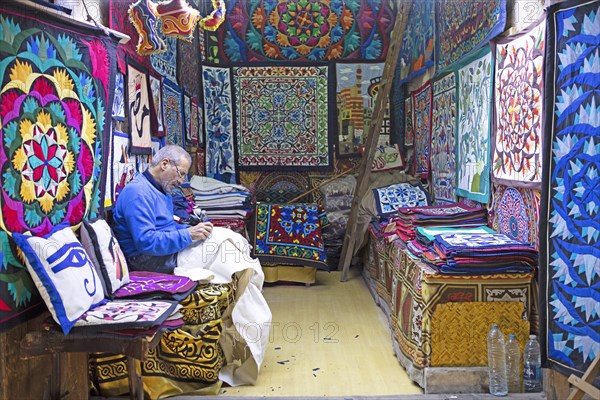 Egyptian man embroidering a cushion in a shop