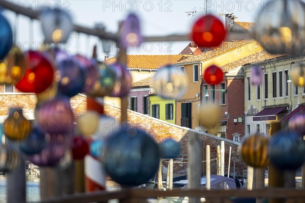 Glass art hangs in the alleys in front of colourful houses