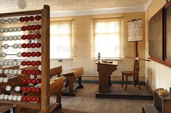 Classroom with teachers desk and ABC board on the left a calculating machine