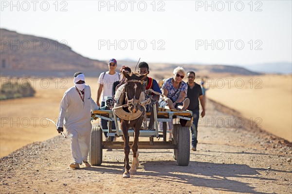 Egyptian men and tourists on a horse cart in the Nubian Desert