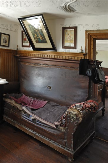 Sofa with saints border in the living room with a view into the sleeping chamber