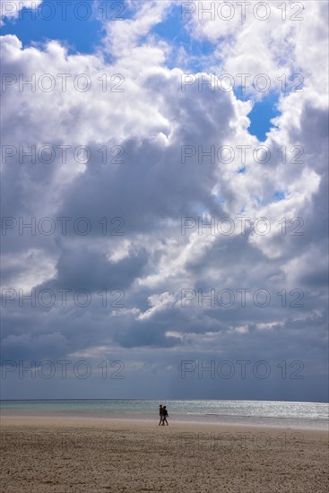 A couple taking a walk on the beach at low tide