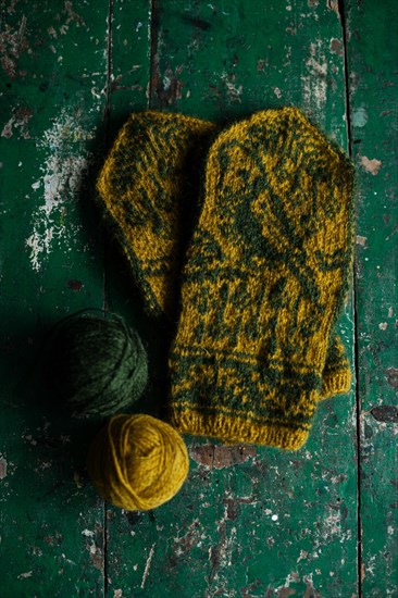 Hand-knitted gloves with pattern next to ball of wool