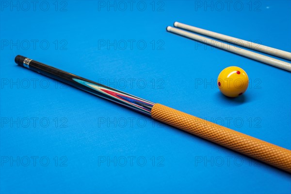 Cue sticks and a yellow ball on a billiard table