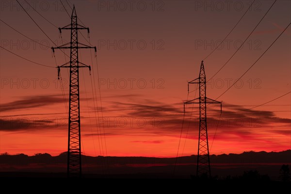 Silhouette of high voltage lines and transmission towers thru the Moravian field at sunrise