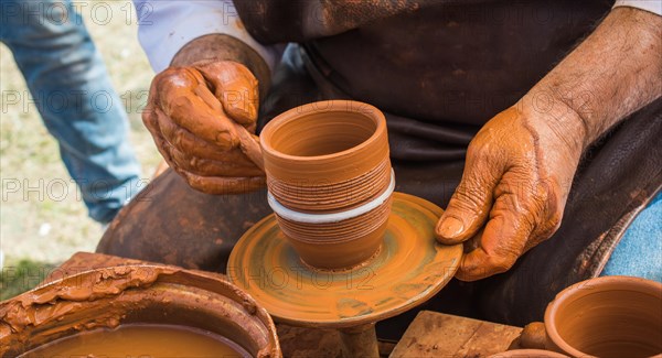 Potter`s hands shaping up the clay of the pot