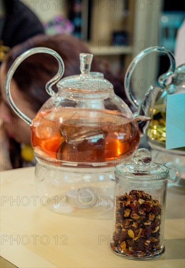 Herbal tea brewed in glass teapot and tea plant in a bottle