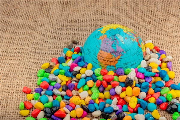 Model globe placed amid colorful pebbles