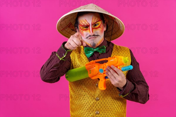 Clown with white facial makeup on a pink background