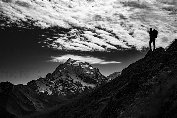 Mountaineer in backlight with cloudy sky in front of Ortler summit massif